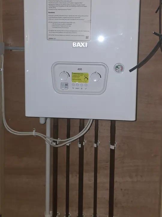 A wall-hung Baxi boiler with its pipework running straight down beneath it.