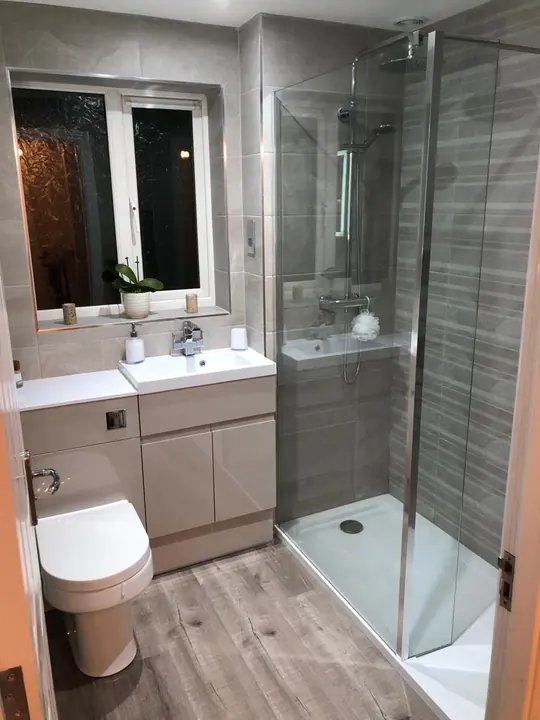A shower room with a combined vanity unit and toilet beside a shower enclosure with a glass screen.