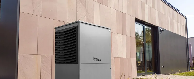 A modern air source heat pump unit installed on the exterior wall of a house.
