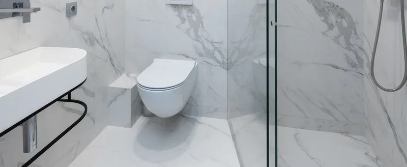 A modern bathroom fitted with a walk-in shower, wall-hung toilet and vanity sink.
