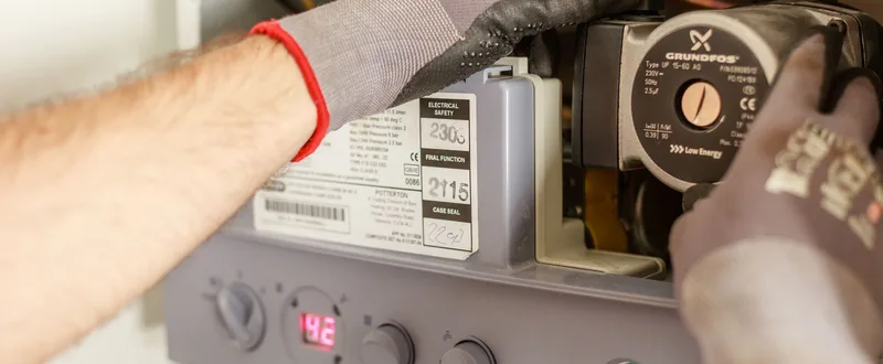 An engineer servicing the internal components of a domestic boiler.